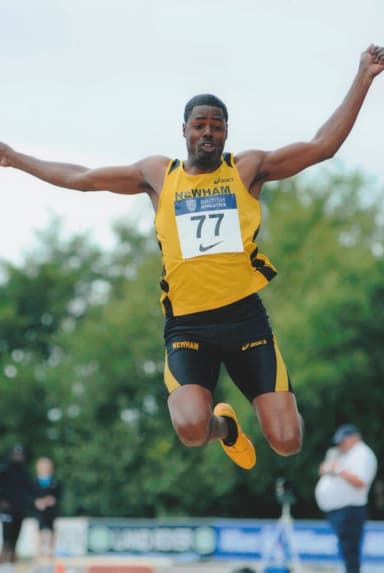 Andre mid-flight in the long jump, bib 77